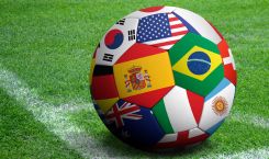 Soccer ball with international flags on grass backgound
